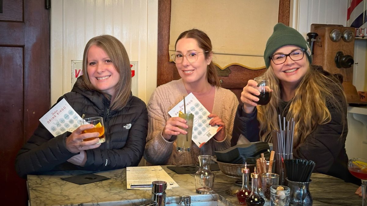 three ladies with drinks and festive drink bingo cards in Daphne's in Edmonds